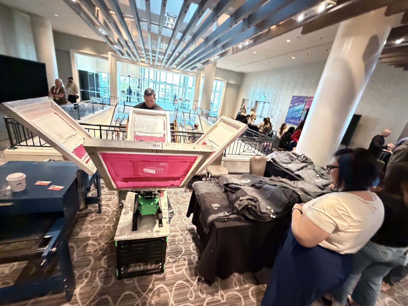 Live printing station set up in a hotel lobby with apparel tables and event guests nearby